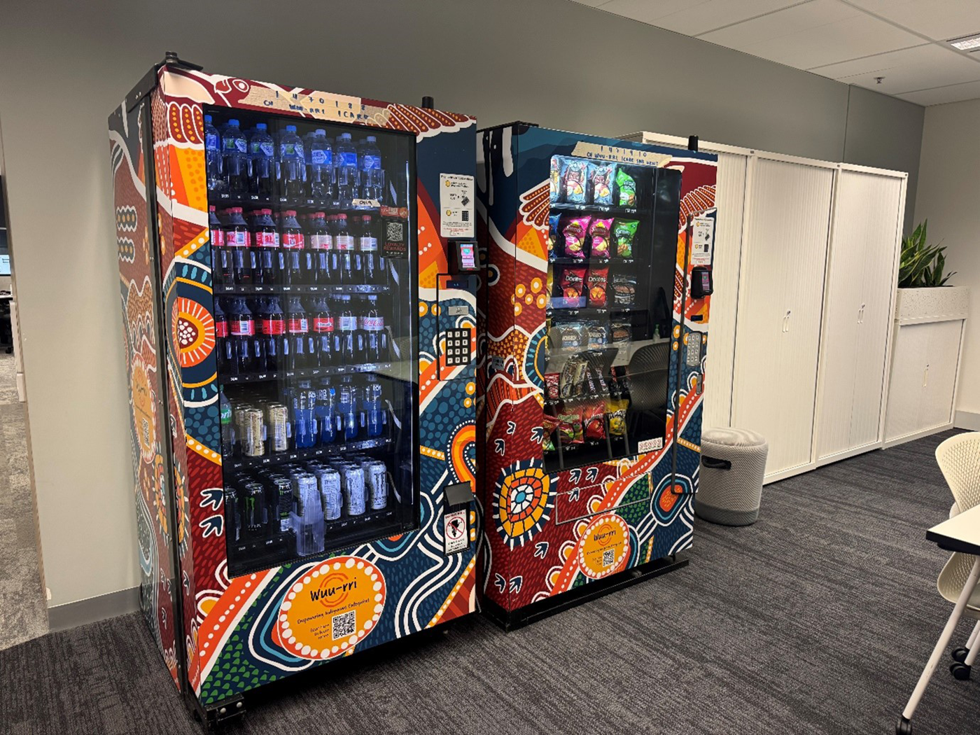 Photo of two Wuu-rri vending machines in an icare office, featuring First Nations artwork.
